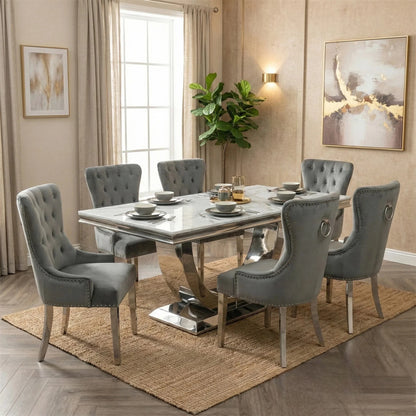 Dining room with a marble table and gray chairs, featuring a rug and wall art.